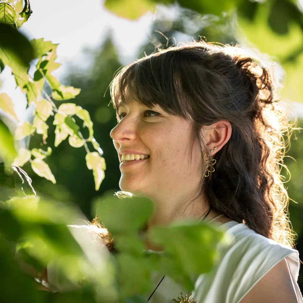 Camille Petit, magnétiseuse à Gières, souriante et entourée de feuillage