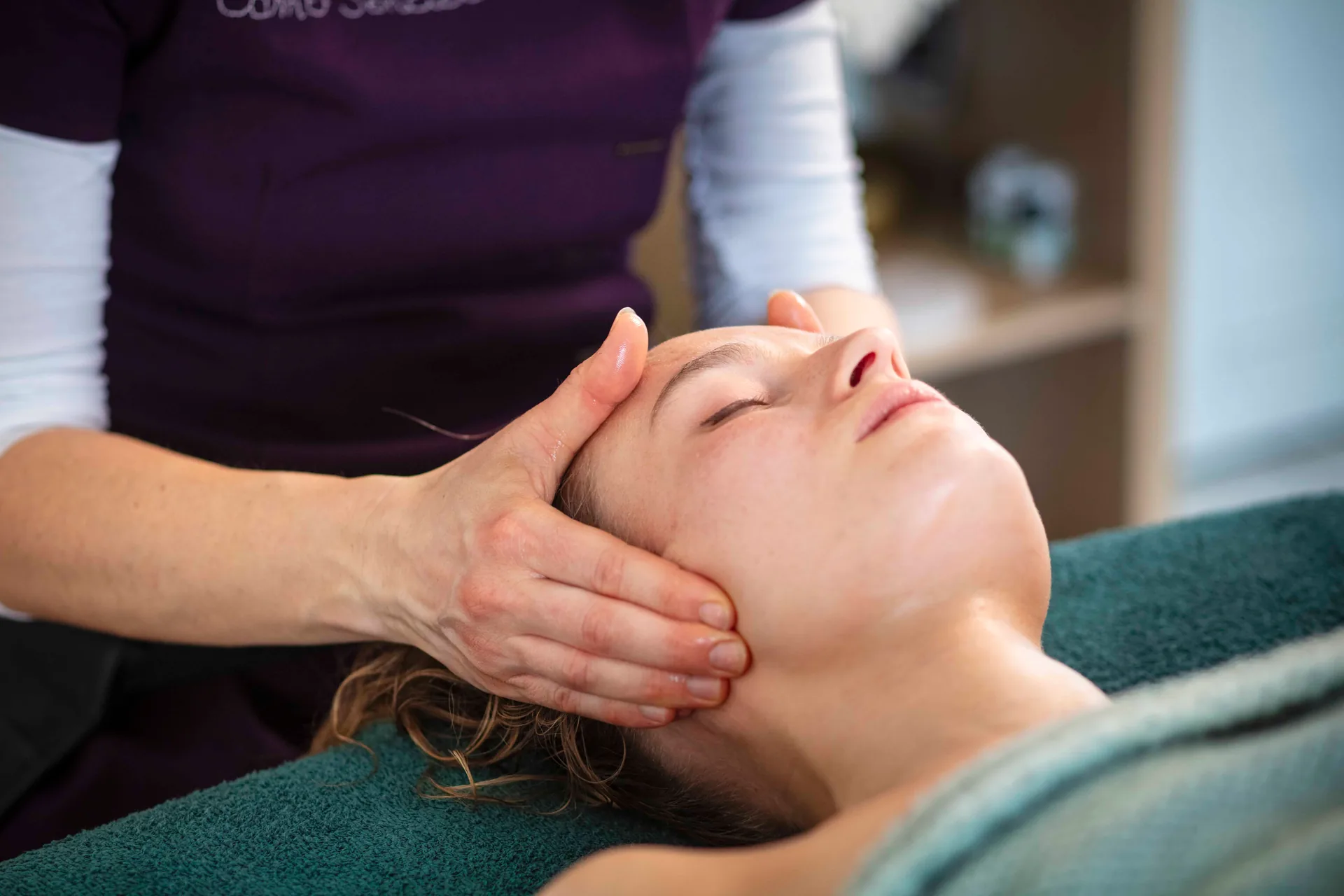Massage du visage, mains posées sur les joues d'une cliente détendue