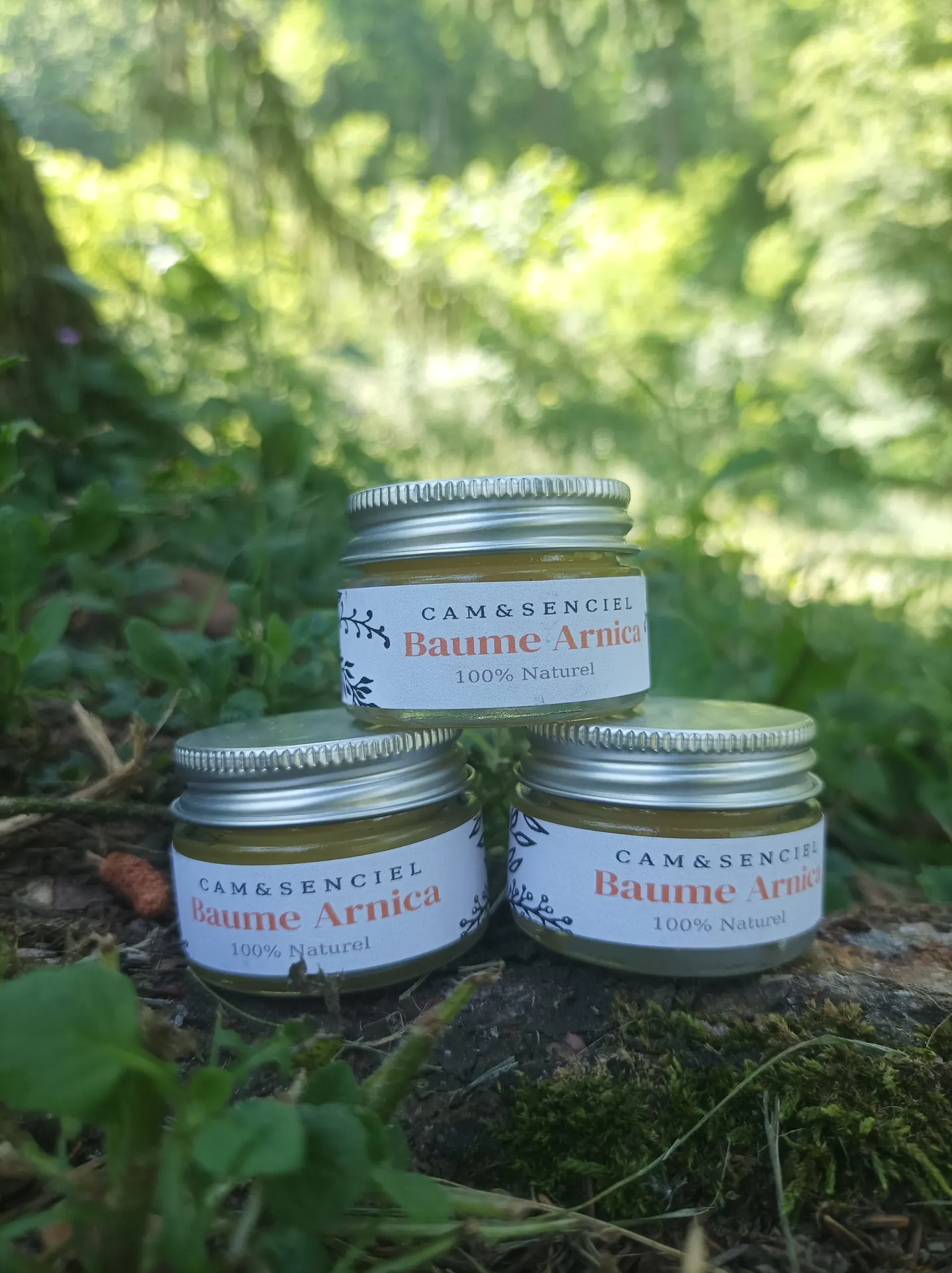 Pots de baume à l'arnica 100 % naturel Cam&Senciel posés dans l'herbe